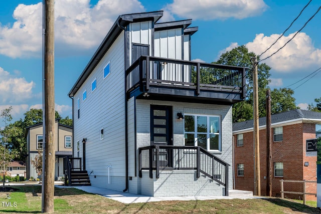 view of front of house featuring a balcony and a front yard