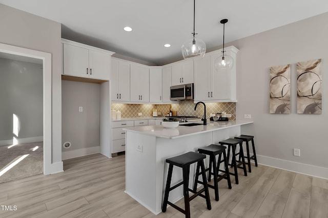 kitchen with white cabinetry, a breakfast bar, hanging light fixtures, and light wood-type flooring