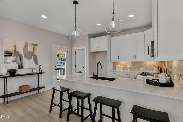 2401 E Main St, Durham, NC 27703 - kitchen featuring stove, light wood finished floors, backsplash, white cabinets, and a peninsula