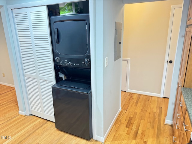 washroom with light wood-type flooring, stacked washing maching and dryer, and electric panel