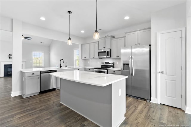 kitchen with dark hardwood / wood-style floors, pendant lighting, sink, kitchen peninsula, and stainless steel appliances