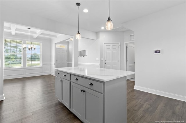 kitchen featuring a center island, gray cabinetry, light stone counters, and decorative light fixtures