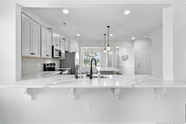 kitchen featuring stainless steel appliances, a kitchen breakfast bar, decorative light fixtures, and kitchen peninsula