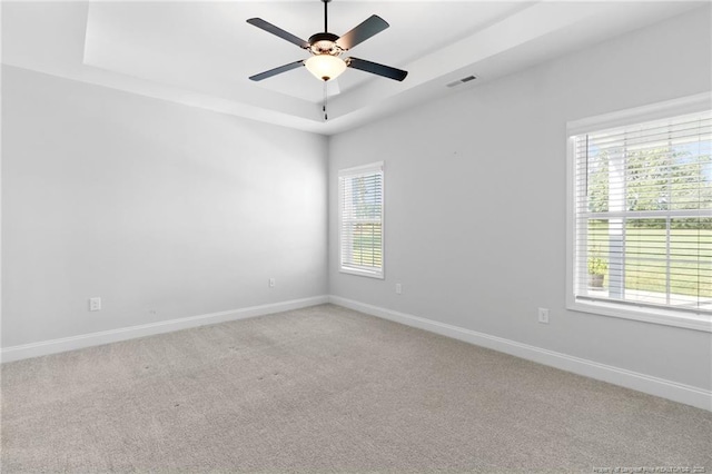 carpeted empty room featuring ceiling fan and a tray ceiling