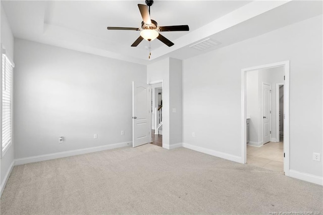 unfurnished bedroom with a tray ceiling, light colored carpet, and ceiling fan