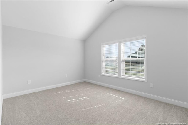 carpeted empty room featuring vaulted ceiling