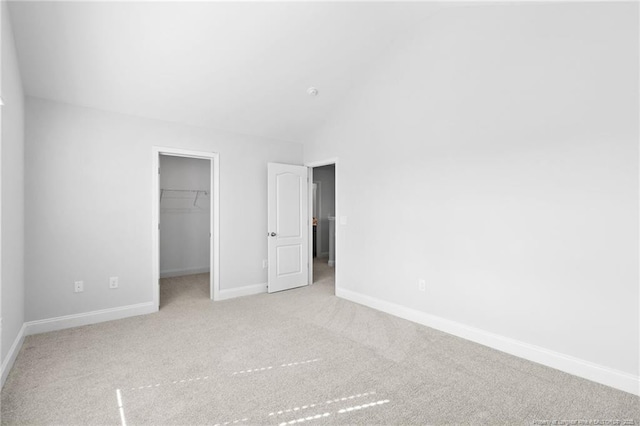 unfurnished bedroom featuring high vaulted ceiling, a spacious closet, light colored carpet, and a closet