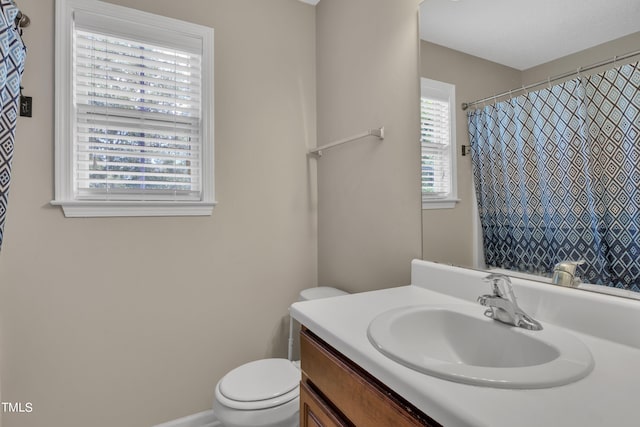 bathroom with curtained shower, toilet, plenty of natural light, and vanity