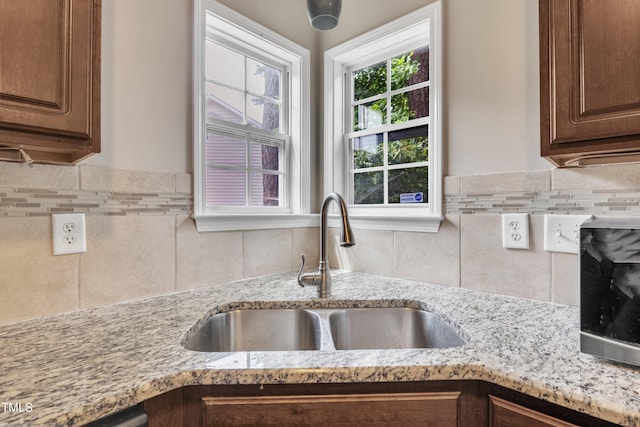 kitchen with sink, light stone countertops, and tasteful backsplash