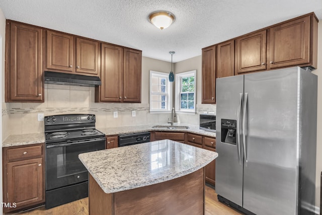 kitchen featuring hanging light fixtures, a center island, light wood-type flooring, sink, and black appliances