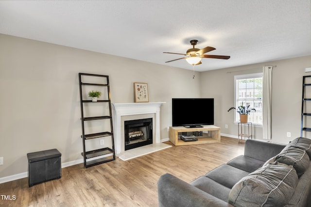 living room featuring ceiling fan, a textured ceiling, and light hardwood / wood-style flooring