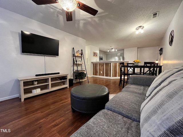 living area with visible vents, ceiling fan, baseboards, wood finished floors, and a textured ceiling