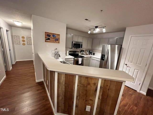 kitchen featuring gray cabinets, kitchen peninsula, appliances with stainless steel finishes, and dark wood-type flooring