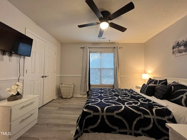 bedroom with light hardwood / wood-style floors, ceiling fan, a textured ceiling, and a closet