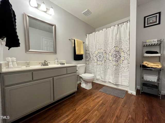 full bathroom featuring visible vents, toilet, vanity, wood finished floors, and a textured ceiling