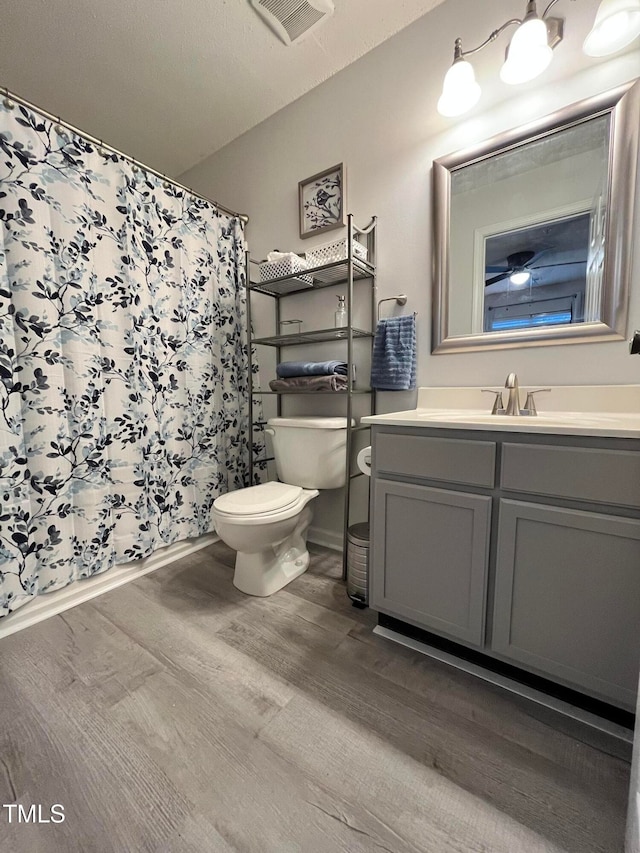 full bath with visible vents, toilet, a shower with curtain, wood finished floors, and vanity