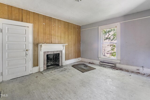 unfurnished living room with a premium fireplace, wooden walls, and hardwood / wood-style flooring