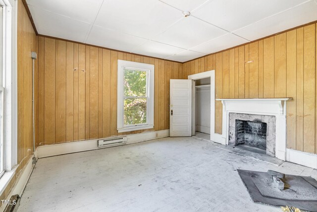 unfurnished living room with a baseboard heating unit, a fireplace, and wooden walls