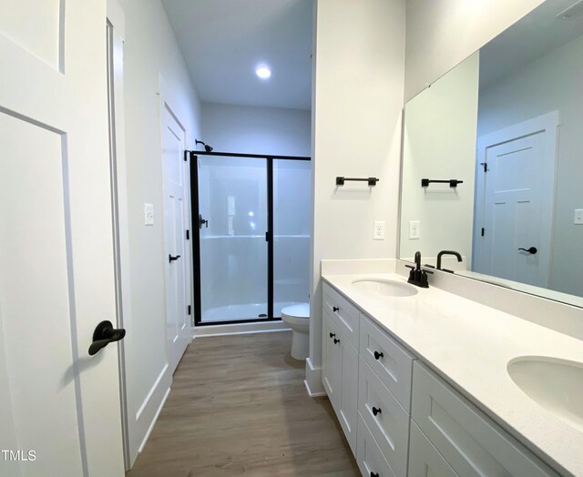 bathroom with vanity, toilet, wood-type flooring, and a shower with shower door