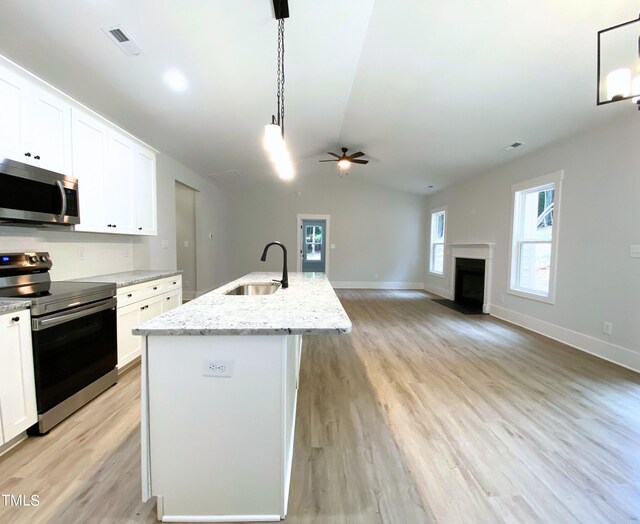 kitchen featuring stainless steel appliances, ceiling fan, sink, pendant lighting, and a kitchen island with sink