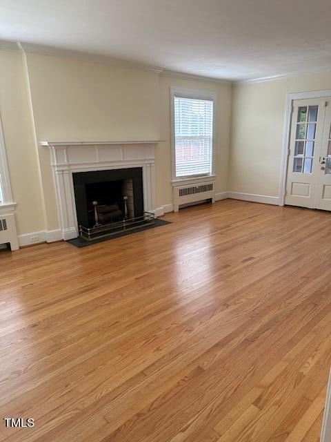 110 S Layton Ave, Dunn, NC 28334 - unfurnished living room featuring baseboards, ornamental molding, light wood-style flooring, a fireplace with flush hearth, and radiator