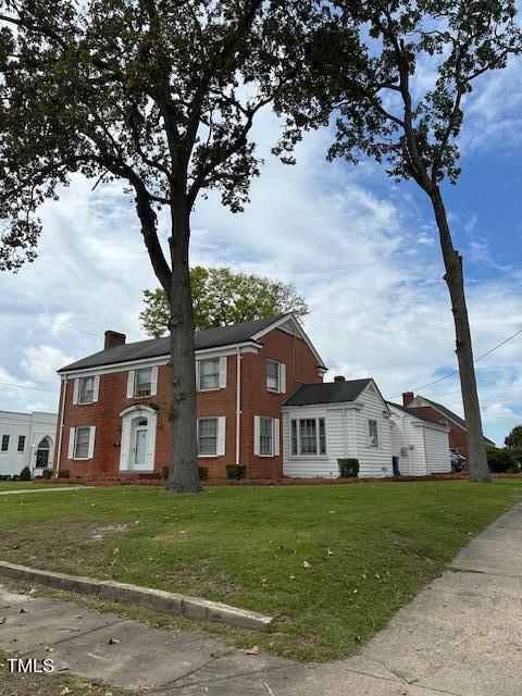 110 S Layton Ave, Dunn, NC 28334 - view of front of house with a chimney, a front yard, and brick siding
