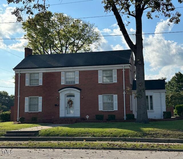 110 S Layton Ave, Dunn, NC 28334 - colonial house featuring a chimney, a front yard, and brick siding