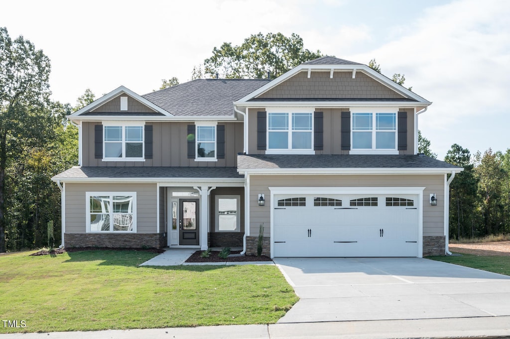 168 Newport Lndg, Garner, NC 27529 - craftsman house featuring driveway, a front yard, an attached garage, and stone siding