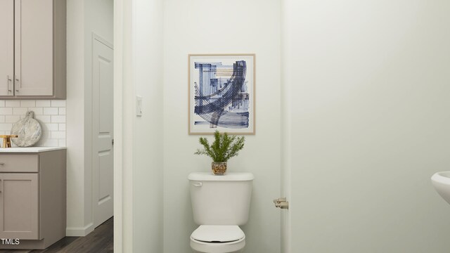 half bath featuring decorative backsplash, toilet, wood finished floors, and vanity