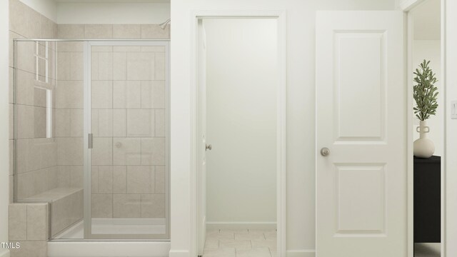 full bathroom with a stall shower and baseboards