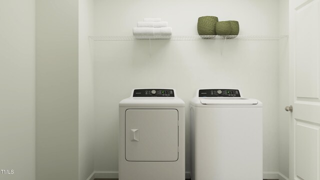 clothes washing area featuring baseboards, separate washer and dryer, and laundry area