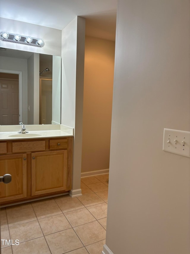 bathroom with tile patterned flooring, vanity, and walk in shower