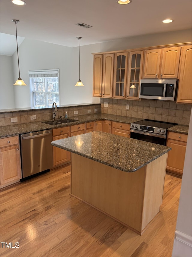 kitchen featuring sink, stainless steel appliances, hanging light fixtures, and light hardwood / wood-style flooring