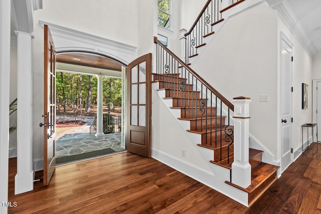 entryway featuring ornate columns, crown molding, and hardwood / wood-style floors