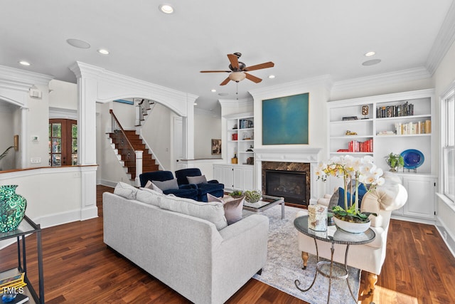 living room featuring a fireplace, dark hardwood / wood-style floors, ornamental molding, built in shelves, and ceiling fan