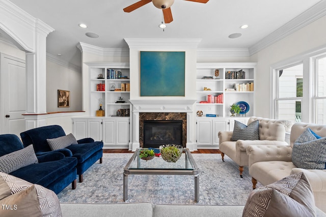 living room featuring ornamental molding, a premium fireplace, light hardwood / wood-style floors, and ceiling fan