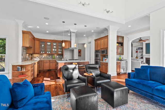 living room featuring ornate columns, ornamental molding, sink, dark hardwood / wood-style flooring, and ceiling fan