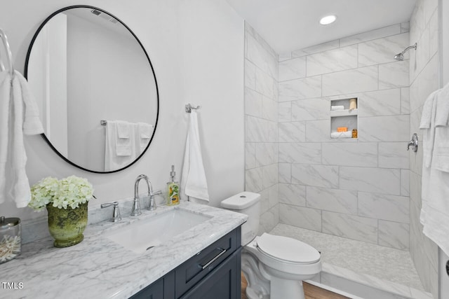 bathroom with vanity, tiled shower, and toilet