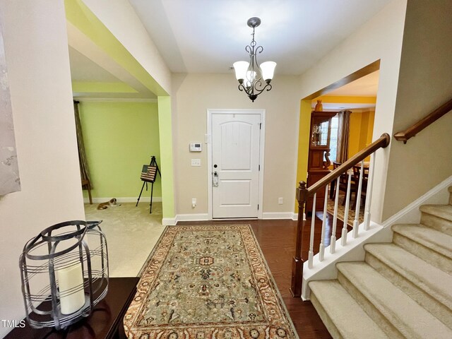 entryway with an inviting chandelier and dark wood-type flooring