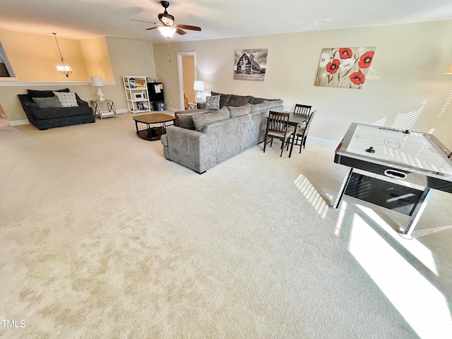 carpeted living room featuring ceiling fan with notable chandelier