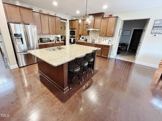 kitchen featuring a breakfast bar area, an island with sink, dark wood-type flooring, sink, and stainless steel appliances