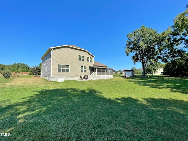 rear view of house featuring a yard, a sunroom, and a shed