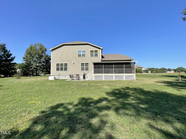 back of property with a patio, a lawn, and a sunroom