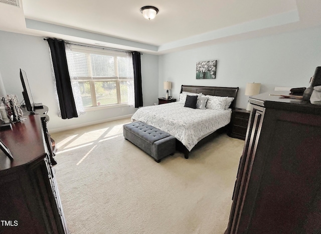 bedroom with light colored carpet and a raised ceiling