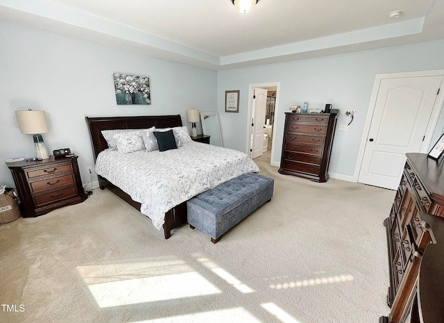 carpeted bedroom with ensuite bath and a tray ceiling