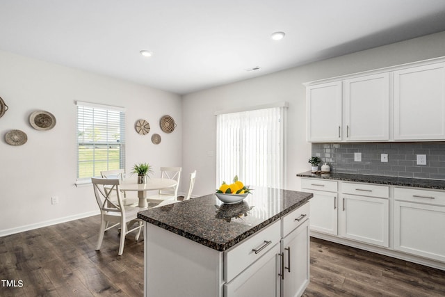 kitchen featuring a kitchen island, dark hardwood / wood-style floors, tasteful backsplash, dark stone countertops, and white cabinets