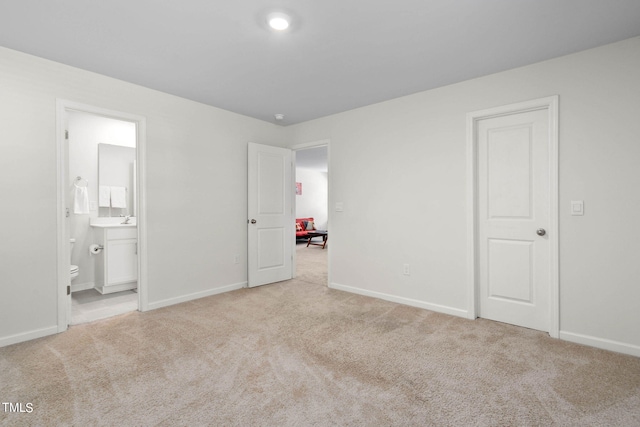 unfurnished bedroom with ensuite bath and light colored carpet