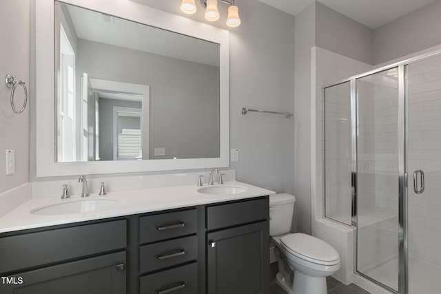 bathroom featuring vanity, a shower with shower door, and toilet