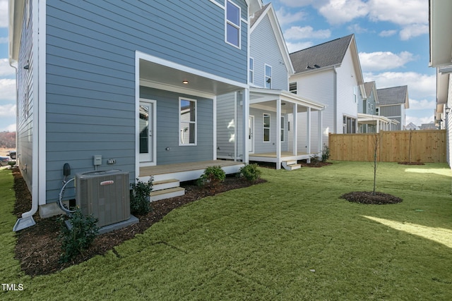 back of property featuring cooling unit and a yard