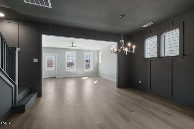 interior space with ceiling fan with notable chandelier and light wood-type flooring